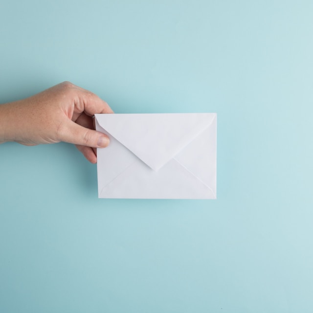 A hand holding a white envelope